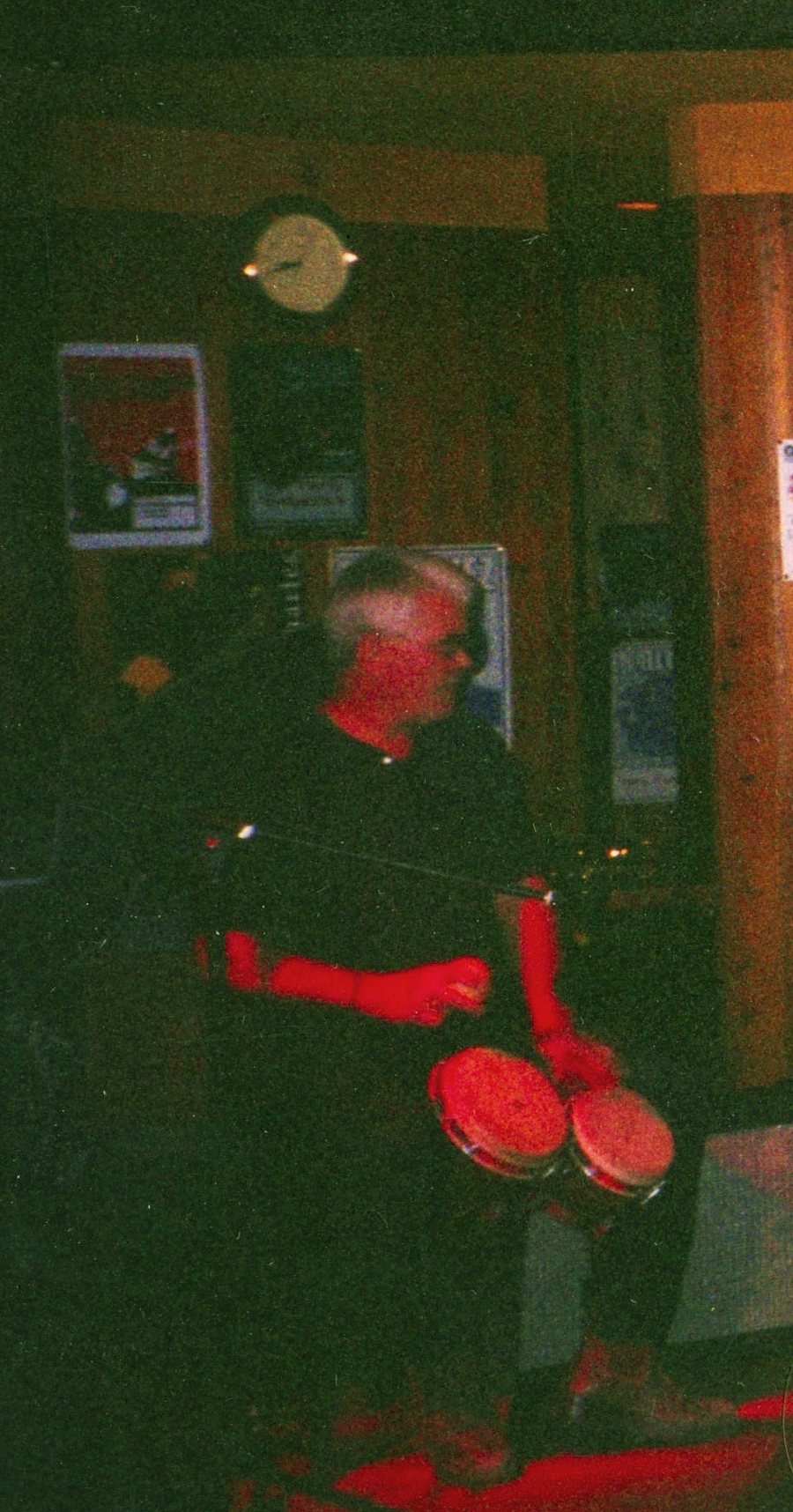 A percussionist behind bongos, lit red from below.