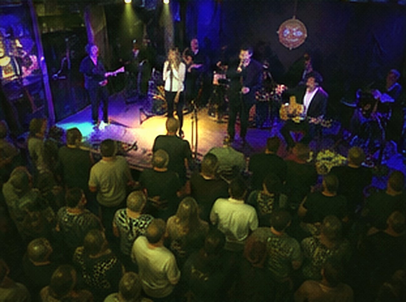 A packed club seen from above, the band on a small stage below a standing crowd.